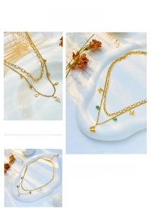 Detail of layered gold stainless steel necklaces with butterfly and star pendants