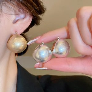 Close-up of matte gold and silver U-shaped basket earrings on female model