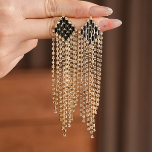 Detailed view of long gold tassel earrings with black diamond panels and sparkling rhinestones