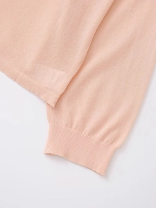 Gros plan du pull rose en maille fine avec détails de poignet côtelé et texture