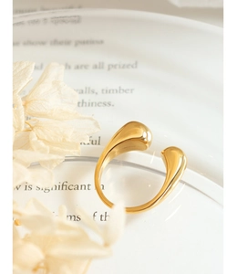 Macro detail of 18k gold plated teardrop open ring on elegant white decorative plate