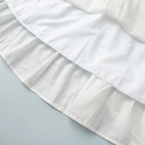 Close-up of white cotton blend fabric showing breathable cross-weave texture and pleat details