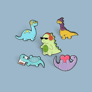 Detail view of colorful cartoon dinosaur enamel pin set on blue-grey background