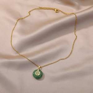 Close-up of green jade donut pendant with gold Fu character on champagne silk fabric