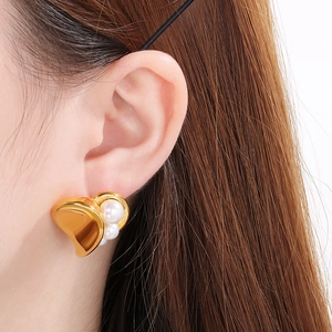Close-up of a model wearing a gold irregular heart-shaped pearl stud earring