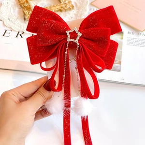 Detail of red velvet bow hair clip with rhinestone star charm and white pompom tassels