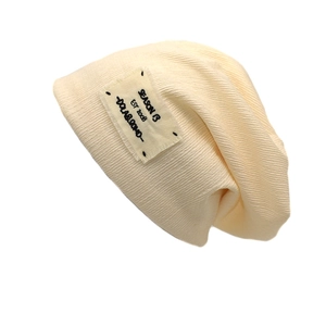 Berretto in maglia crema con toppa vintage e trama a costine su sfondo bianco puro