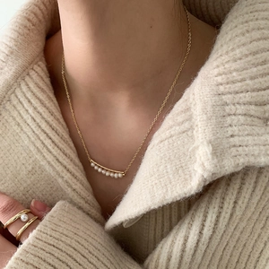 Close-up of elegant baroque pearl necklace and matching gold ring on a knit sweater