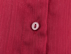 Détail macro d'une chemise en mousseline bordeaux avec tissu texturé et bouton rond assorti