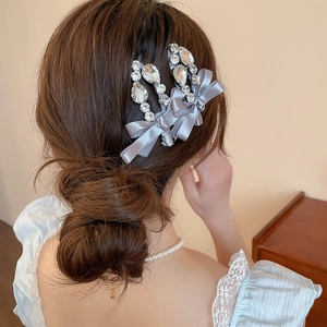 Détail de barrettes noeuds en soie grise avec cristaux sur un chignon élégant