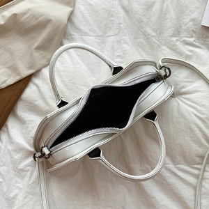 Top view of open white faux leather bag showing black interior and silver hardware zipper