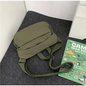 Army green nylon crossbody bag detail with textured shoulder strap and black zipper