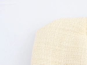 Detailansicht aus beigem Tweed-Stoff mit goldenen Knöpfen am trägerlosen Kleid