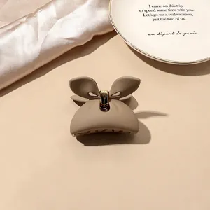 Macro view of matte khaki butterfly hair claw clip with golden metal spring detail