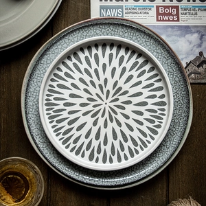 Minimalist white ceramic steak plate with black droplet pattern on dark wood table