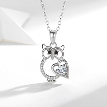 Macro detail of silver owl pendant featuring heart-shaped zircon and sparkling stones