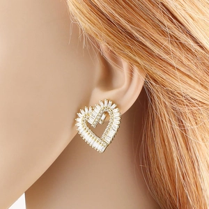 Pendientes de corazón dorados con cristales de circón y letra F en una modelo