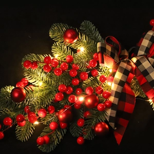 Christmas pine needle garland with red berries, LED lights, and buffalo plaid bow decoration