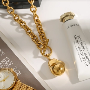 Dettaglio ravvicinato della collana a catena dorata con chiusura OT e ciondolo unico