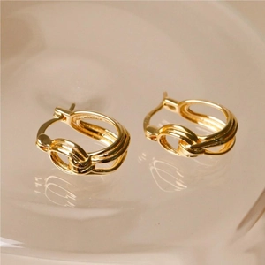 Detailed close-up of gold-plated twisted hoop earrings with a knotted texture design