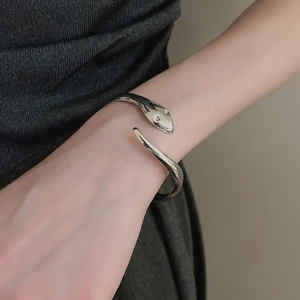 Detailed close-up of a silver snake-shaped cuff bracelet on a female wrist