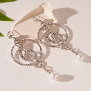 Detailed close-up of musical note earrings with rhinestones and pearls on a white plaster base