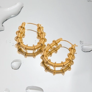 Orecchini a U in acciaio inossidabile placcato oro 18K su superficie d'acqua riflettente