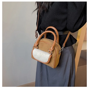 Close-up of brown suede handbag with white faux shearling detail and silver hardware