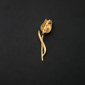 Elegant gold tulip flower brooch with detailed petals and stem on a black leather background