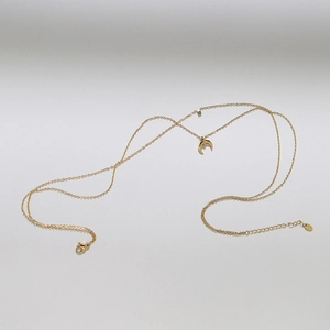 Close-up of gold double-layer necklace featuring a crescent pendant and green gemstone