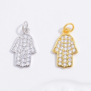 Detailed view of silver and gold Hamsa hand pendants with micro-pave white zircon