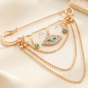Makroaufnahme einer goldenen Brosche mit bösem Blick und funkelnden Strass-Quasten