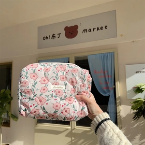 Detail of floral quilted cotton makeup bag featuring pink flowers and metal zipper closure