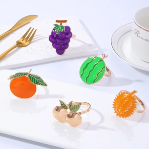 Detail showing five assorted metal fruit napkin rings on a white marble tray table setting