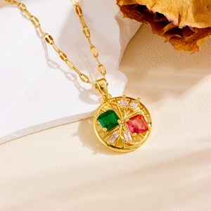 Detail of gold necklace pendant with green and pink gemstones on white stone background