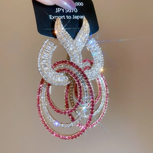 Macro detail of luxury gold-plated geometric hoop earrings with sparkling rhinestones