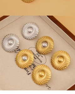 Dettaglio degli orecchini a bottone con trama a spirale in finitura oro e argento