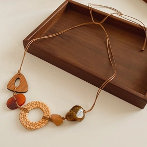 Détail d'un collier ethnique avec pendentifs en résine et rotin sur surface beige