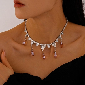 Detailed view of silver tennis necklace with five sparkling pink teardrop crystals