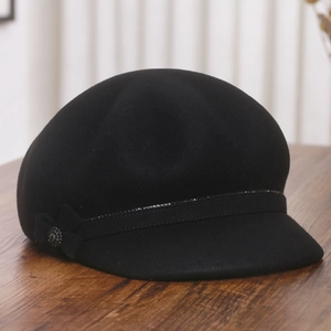 Detail of wool newsboy hat featuring a sequin band and rhinestone bow on wood