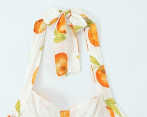 Detailansicht eines Neckholder-Tops mit Schleifenband und frischem Orangen-Print-Muster