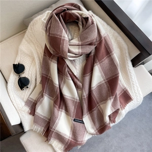 Close-up of soft cashmere scarf featuring brown plaid pattern and elegant fringe detail