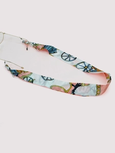 Detail view of retro printed ribbon eyewear strap with golden metal hooks and silk texture