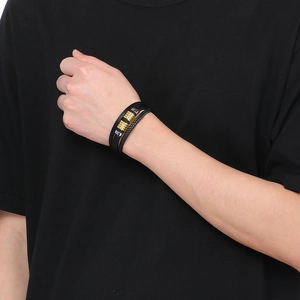 Close-up of a multi-layer black braided leather bracelet with gold and silver beads on wrist