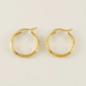 Macro detail of 18K gold stainless steel hoop earrings with Greek key pattern engraving
