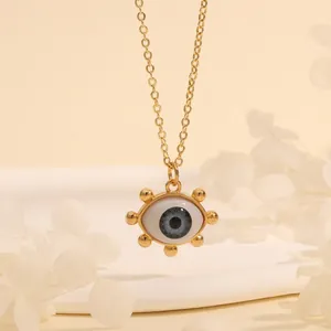 Detail of 18K gold-plated Evil Eye pendant necklace on an elegant minimalist pedestal