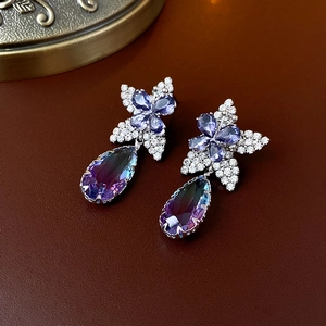 Détail de boucles d'oreilles fleur en argent avec pierre goutte en dégradé bleu-violet