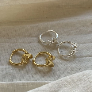 Close-up of twisted 925 sterling silver hoop earrings in gold and silver on white knit