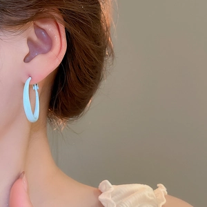Close-up of a model wearing a light blue minimalist smooth hoop earring in enamel finish