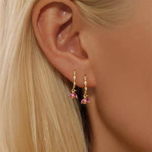 Macro detail of gold hoop earring with pink gemstone pendant on a female model